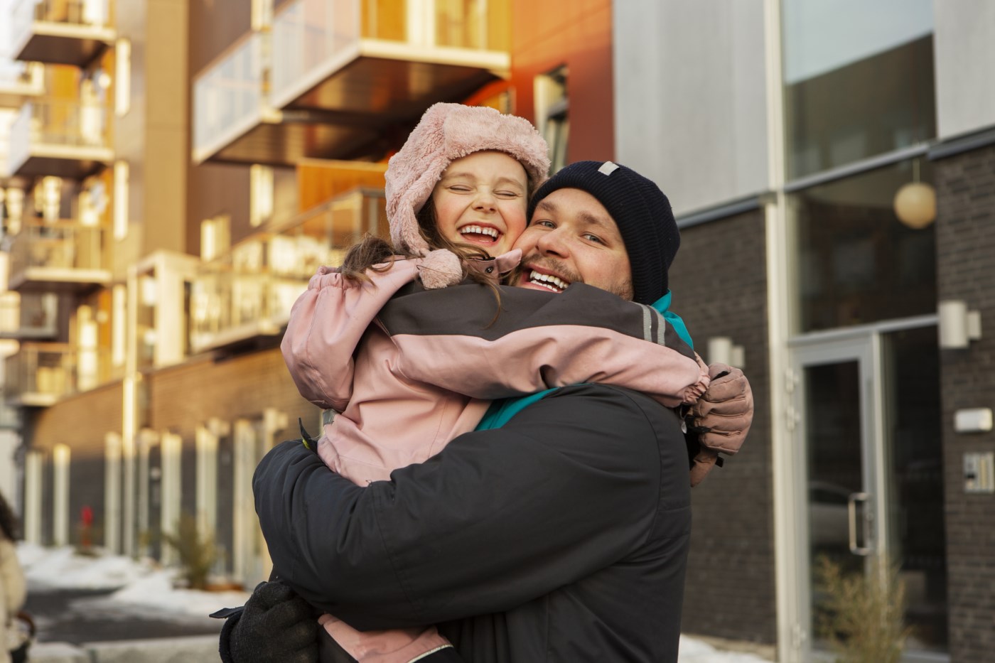 Far og datter klemmer ute