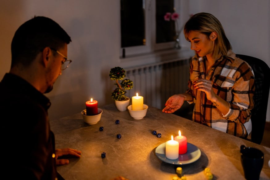 Par spiller spill med levende lys på bordet.