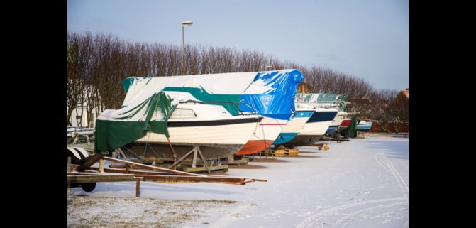 Båter ligger på land med presenning. Foto