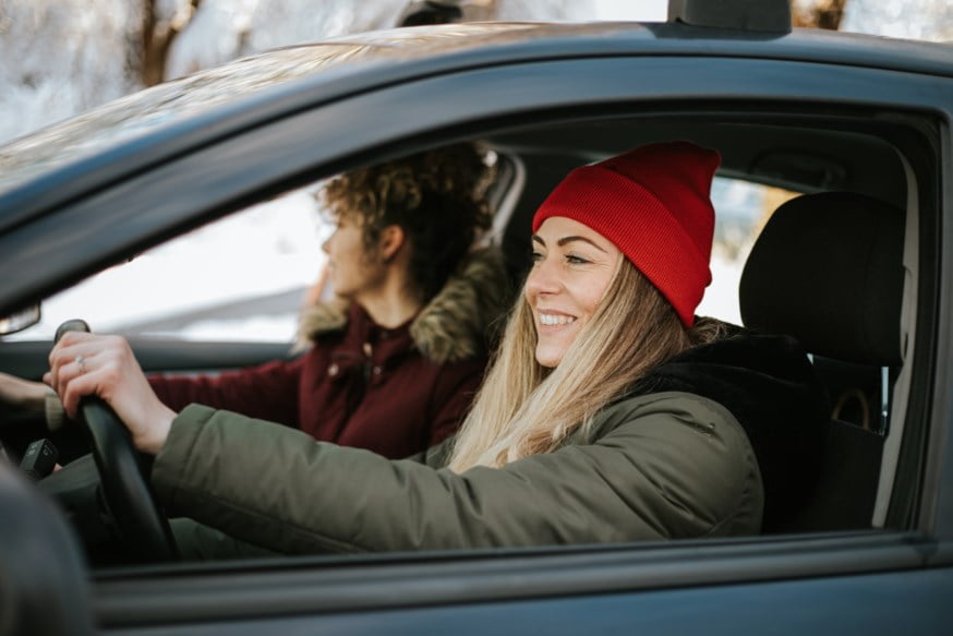 Kvinne med rød hatt, kjører bil. Foto