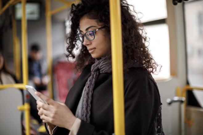 Kvinne ser på telefonen sin på bussen. Foto