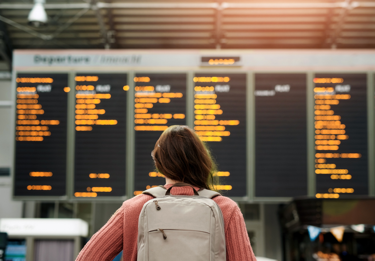 Kvinne ser på tidstabell på flyplass Kvinne ser på tidstabell på flyplass